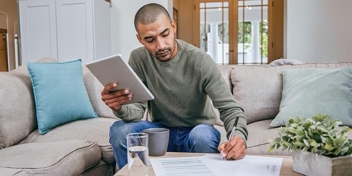 A man sitting on the couch writing papers.