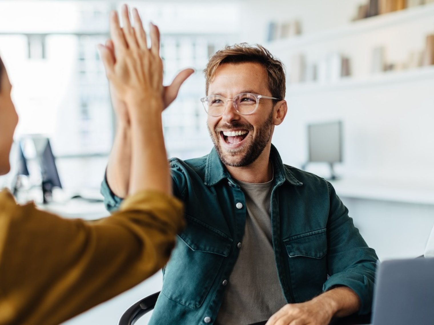 A man and woman high five to celebrate a success.