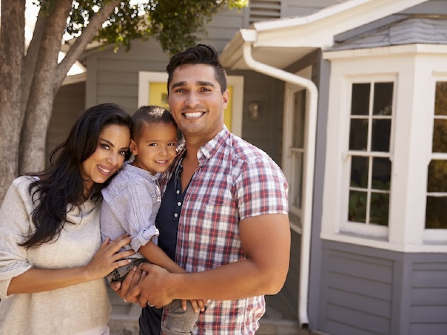 Hispanic family standing outside of home.