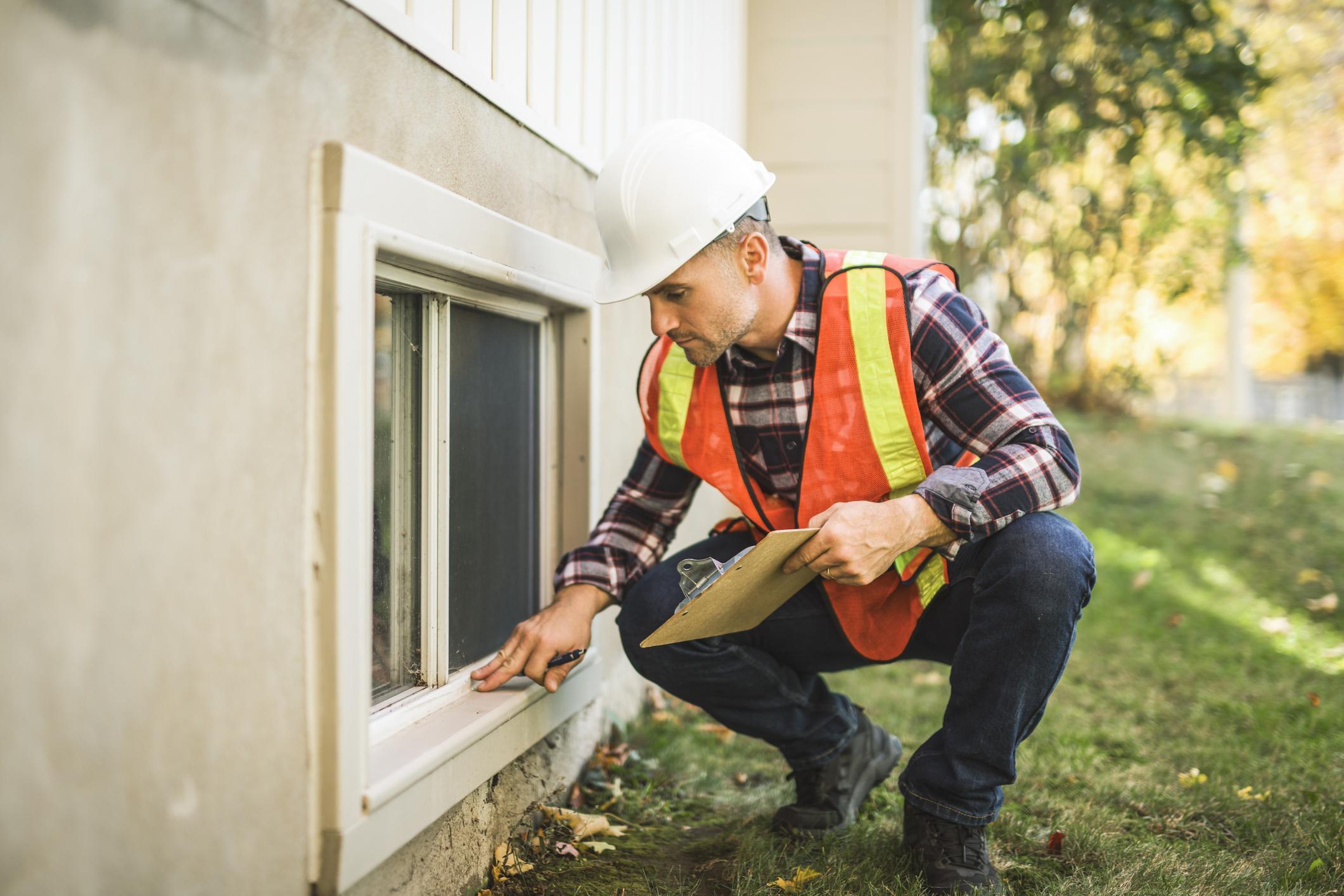 A man inspecting a house window outside during the VA appraisal.