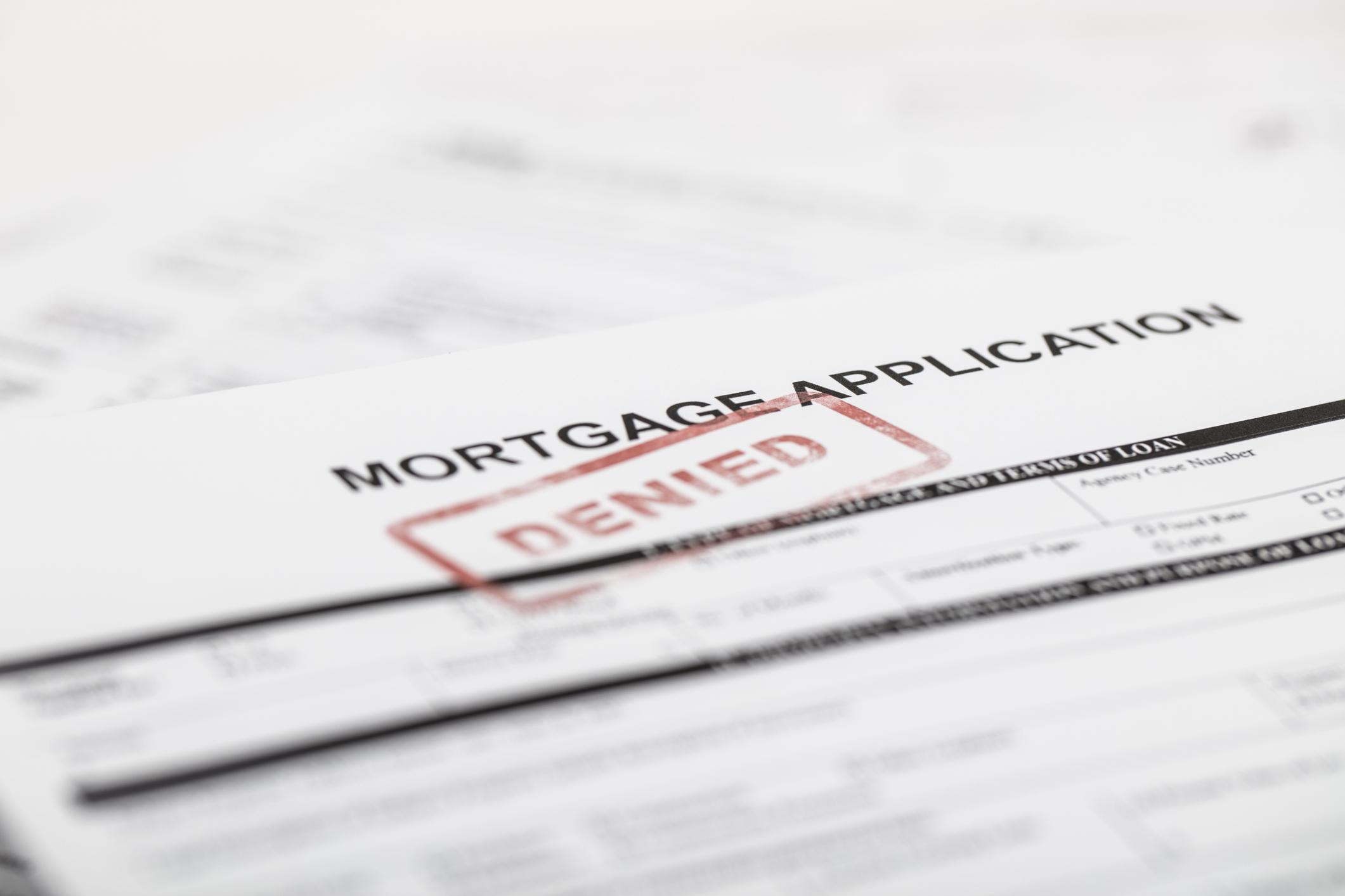 A paper mortgage application with "denied" stamped across it.